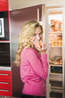 Portrait of a woman standing in front a refrigerator and eating an apricot