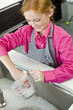 Close-up of a girl washing a measuring jug at a sink