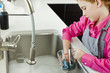 Girl washing a measuring jug at a sink