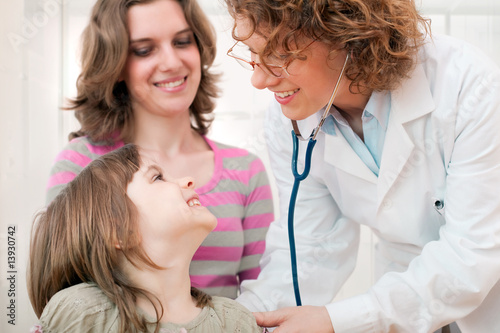 Foto: Mature doctor examining happy child, smiling. Mature doctor examining happy child, smiling.