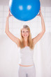 Pretty young blond hair girl holding blue pilates ball