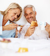 Elderly couple having breakfast on the bed
