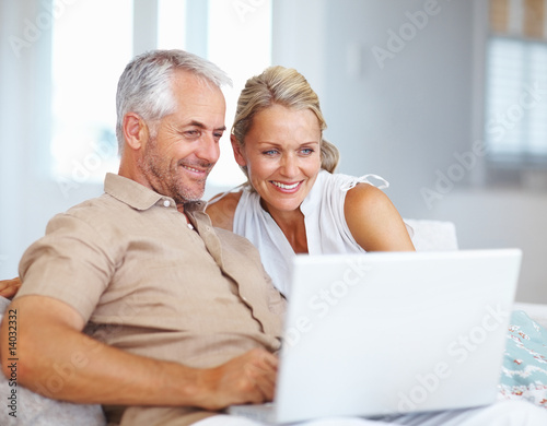 A happy aged couple surfing on a laptop