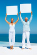 Senior couple at the beach holding a billboard