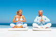 Healthy senior couple meditating at the sea shore