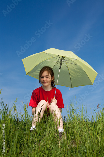 Photo: Girl sitting on green meadow holding umbrella Girl sitting on green meadow holding umbrella