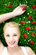Young woman lying on grass with strawberries