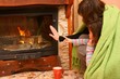 Woman with daughter warming hand at fireplace