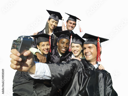 Photo: Graduates in caps and gowns taking photograph of themselves, cut out Graduates in caps and gowns taking photograph of themselves, cut out