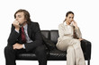 Anxious businessman and businesswoman sitting on sofa, cut out