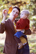 A young mother showing an autumn leaf to her baby