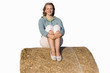 Teenage girl on hay bale, knees to chest, smiling, portrait, cut out