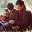 A young family sitting on the grass in autumn time