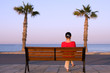 Photo: Lonely girl sits on a bench near sea beach Lonely girl sits on a bench near sea beach