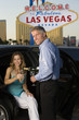 Photo: Mid-adult couple sitting in limousine and drinking champagne in front of Welcome to Las Vegas sign Mid-adult couple sitting in limousine and drinking champagne in front of Welcome to Las Vegas sign
