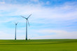 canvas print picture Wind turbines farm in green field over cloudy sky