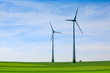 canvas print picture Wind turbines farm in green field over cloudy sky