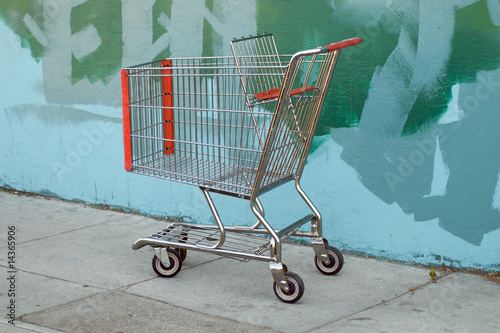 Photo: Urban scene with a shopping cart parked by a painted alley wall Urban scene with a shopping cart parked by a painted alley wall