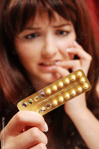 Photo: Worried woman looking at her pills Worried woman looking at her pills