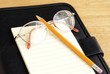 Eyeglasses, pencil and notepad