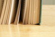 Old book with green hard cover standing on a wooden table