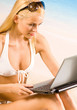 Young woman in bikini with laptop on the beach