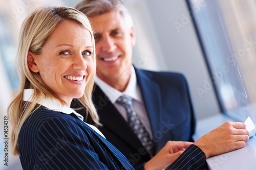 Foto: A smiling business woman with coworker at the back A smiling business woman with coworker at the back
