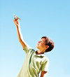 Young boy playing with an airplane with the blue sky as the back