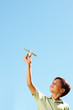 Happy boy playing with an aeroplane over a clear blue sky