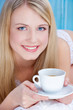 Pretty blond woman drinking coffee in bed