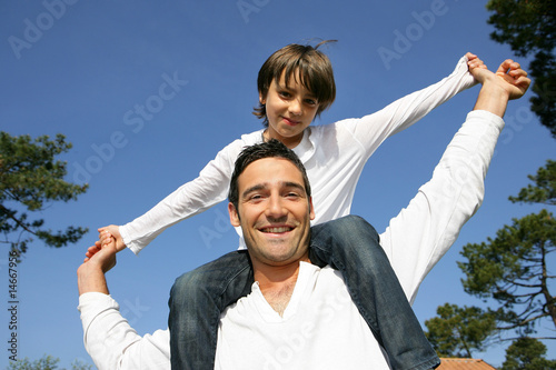 Photo: Petit garçon assis sur les épaules de son père Petit garçon assis sur les épaules de son père