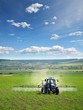 Farming tractor plowing and spraying on field vertical