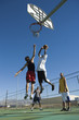 Photo: Basketball player, mid-air, shooting ball into hoop while another guards him, low angle view Basketball player, mid-air, shooting ball into hoop while another guards him, low angle view