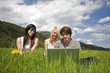 Foto: Junge Leute mit Laptop in Blumenwiese Junge Leute mit Laptop in Blumenwiese