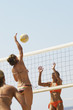 Photo: Beach volleyball player jumping to spike volleyball over net, opponent defending Beach volleyball player jumping to spike volleyball over net, opponent defending