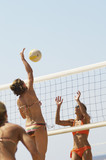 Photo: Beach volleyball player jumping to spike volleyball over net, opponent defending Beach volleyball player jumping to spike volleyball over net, opponent defending