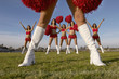 Cheerleader in white knee high boots, low section with cheerleaders behind