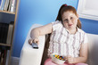 Overweight girl 13-15 Eating Junk Food, holding remote control