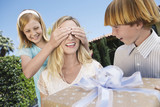 Photo: Daughter covering eyes of mother who's receiving Gift from her Children outside Daughter covering eyes of mother who's receiving Gift from her Children outside