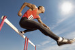 Photo: Male athlete jumping hurdle, mid air Male athlete jumping hurdle, mid air