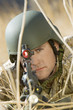 Soldier aiming rifle, hiding in long grass, close-up