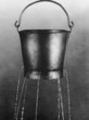 Water poring through holes in bucket, b&w