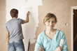 Woman holding paint brush next to man painting interior wall