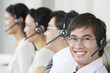 Photo: Row of customer service representatives wearing telephone headsets in office, head and shoulders Row of customer service representatives wearing telephone headsets in office, head and shoulders