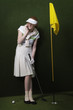 Woman in visor holding golf club by flag in hole