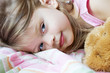 Toddler lying in bed with her teddy bear