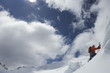 Mountain climber going up snowy slope with axes