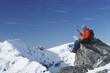Mountain climber using laptop with walkie-talkie on mountain peak
