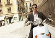Man riding scooter through old town, portrait.
