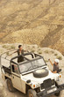 Photo: Man photographing woman standing in four wheel drive car on edge of cliff, elevated view Man photographing woman standing in four wheel drive car on edge of cliff, elevated view